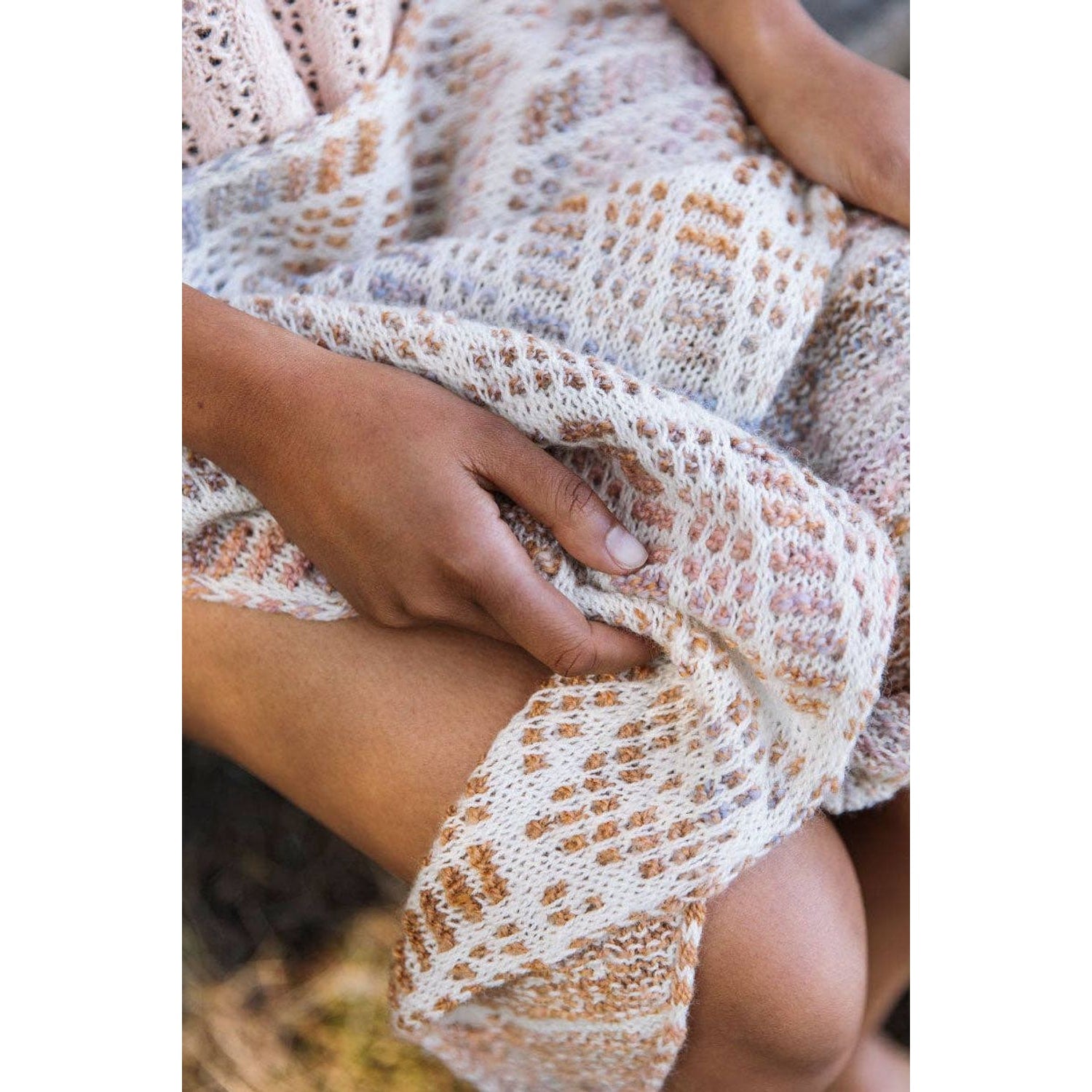 Stylish model holding a knitted shawl from Laine Magazine Issue 25 showcasing intricate patterns