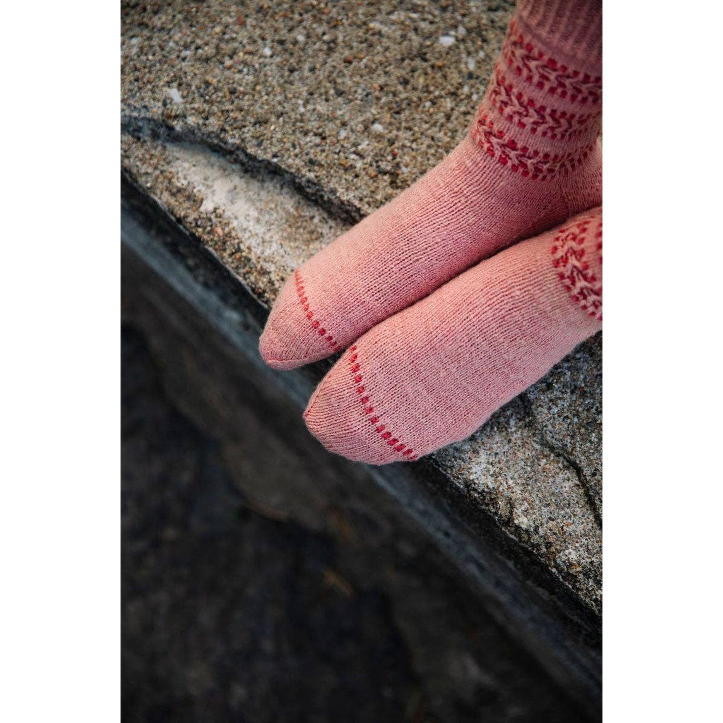 Cozy pink knitted socks with decorative red patterns featured in Laine Magazine Issue 25