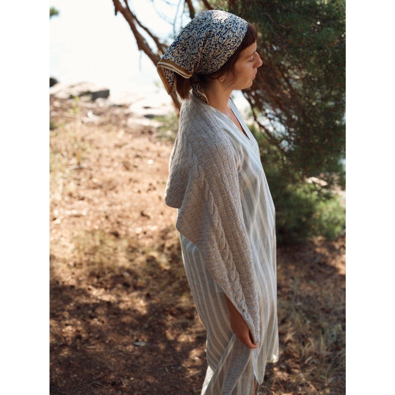 Model wearing a stylish gray shawl and headscarf outdoors with Laine magazine in hand
