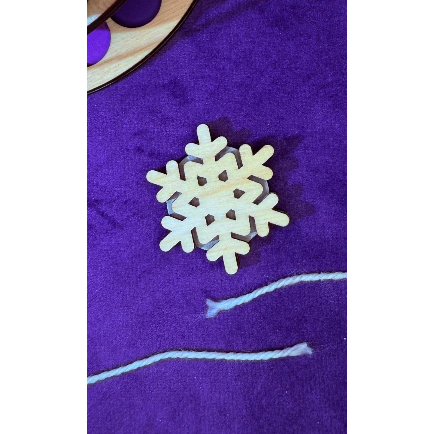 Lemonwood elementary snowflake wooden piece on a purple felt background