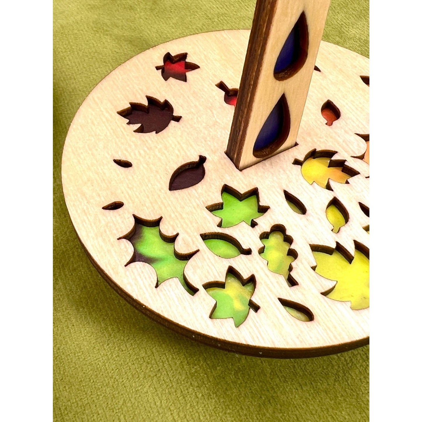 Lemonwood Autumn Tour stitch marker wooden disk with leaf cutouts and multicolor resin insets on green cloth
