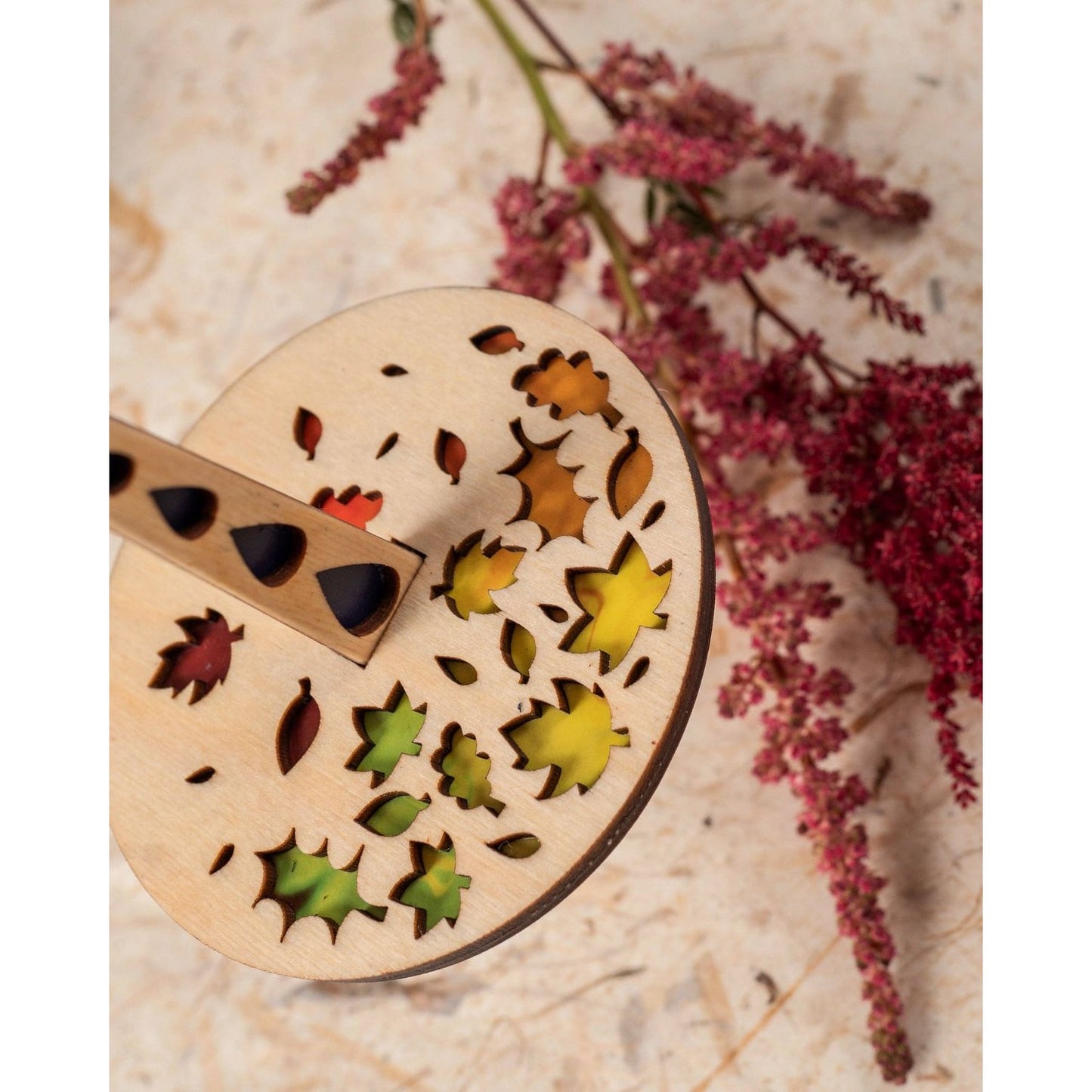Lemonwood Autumn Tour stitch marker laser cut wooden marker with colorful leaf inlays on rustic wood with dried pink flowers