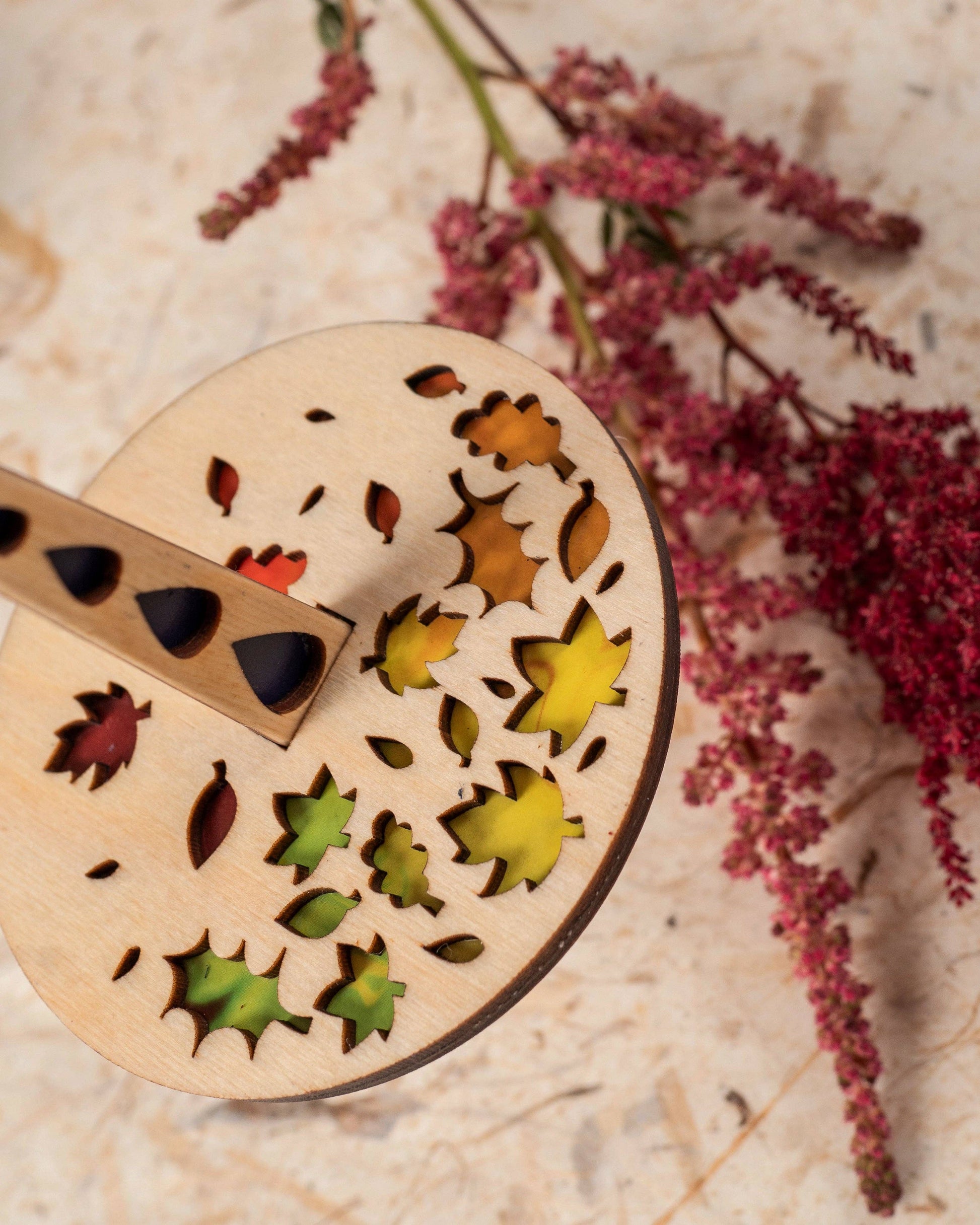 Lemonwood Autumn Tour stitch marker laser cut wooden marker with colorful leaf inlays on rustic wood with dried pink flowers