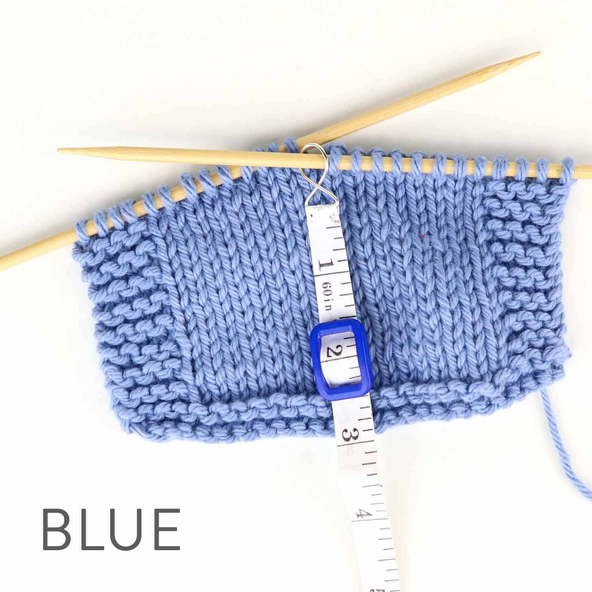 Blue knitted swatch on needles with a tape measure demonstrating measuring with tape