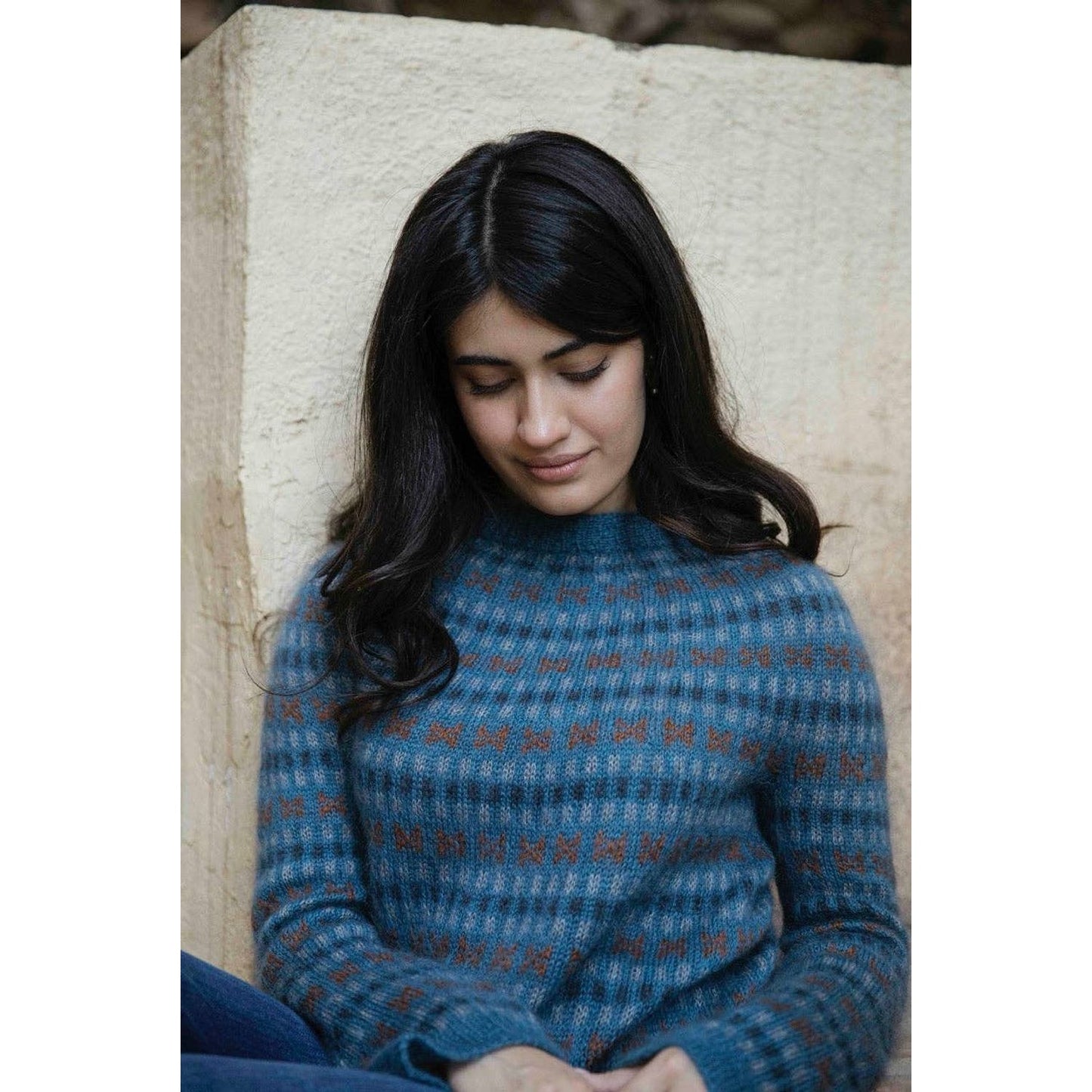 Woman modeling a cozy sweater featuring patterns from the Memory Lane knitting book