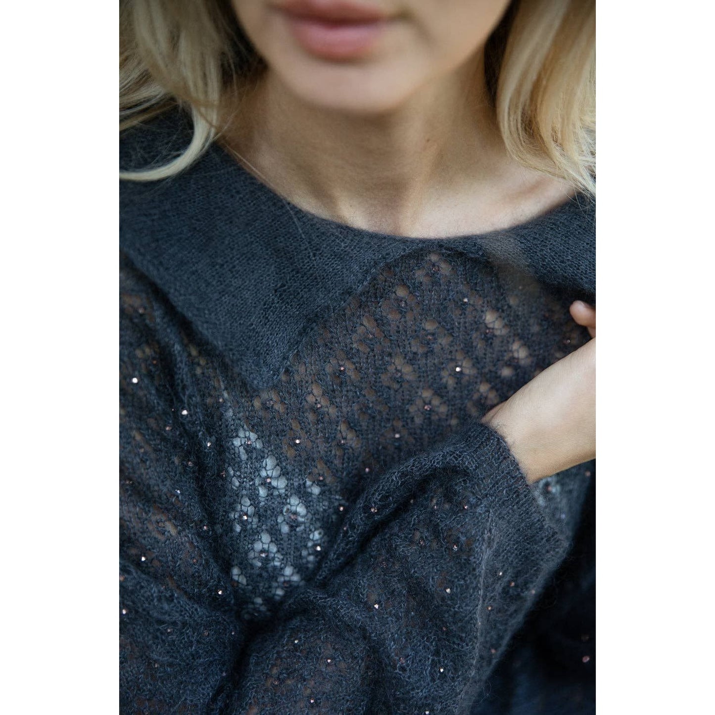 Close-up of a woman wearing a delicate gray knit sweater, showcasing intricate patterns and details from the Memory Lane kni…