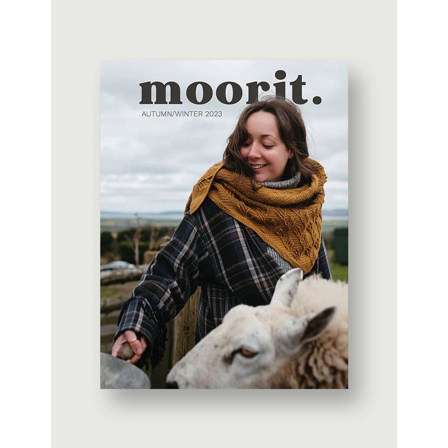 Moorit Magazine crochet patterns magazine cover woman in mustard crochet cowl plaid coat with sheep outdoors