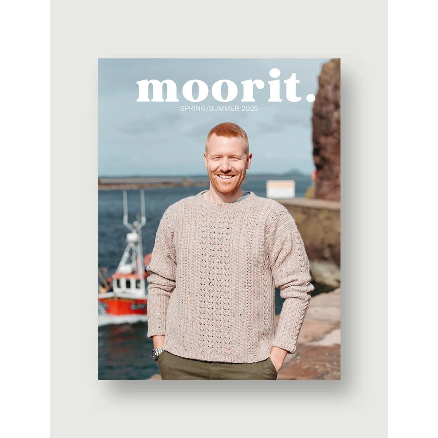 Moorit Magazine crochet patterns cover showing smiling man wearing textured hand crochet sweater by a harbor