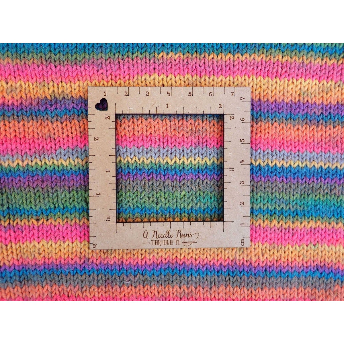 Knitting a gauge swatch with a colorful striped pattern and a measurement square overlay