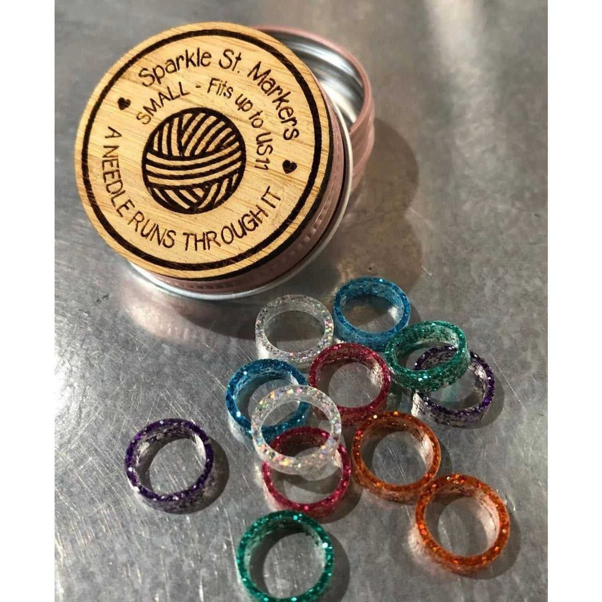 Sparkle stitch markers for crocheting in various colors inside a decorative tin by A Needle Runs Through It