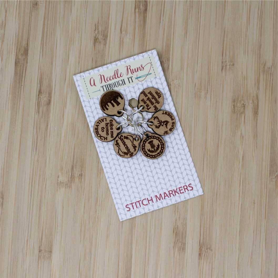 A pack of wooden stitch markers for crocheting with various fun designs by A Needle Runs Through It