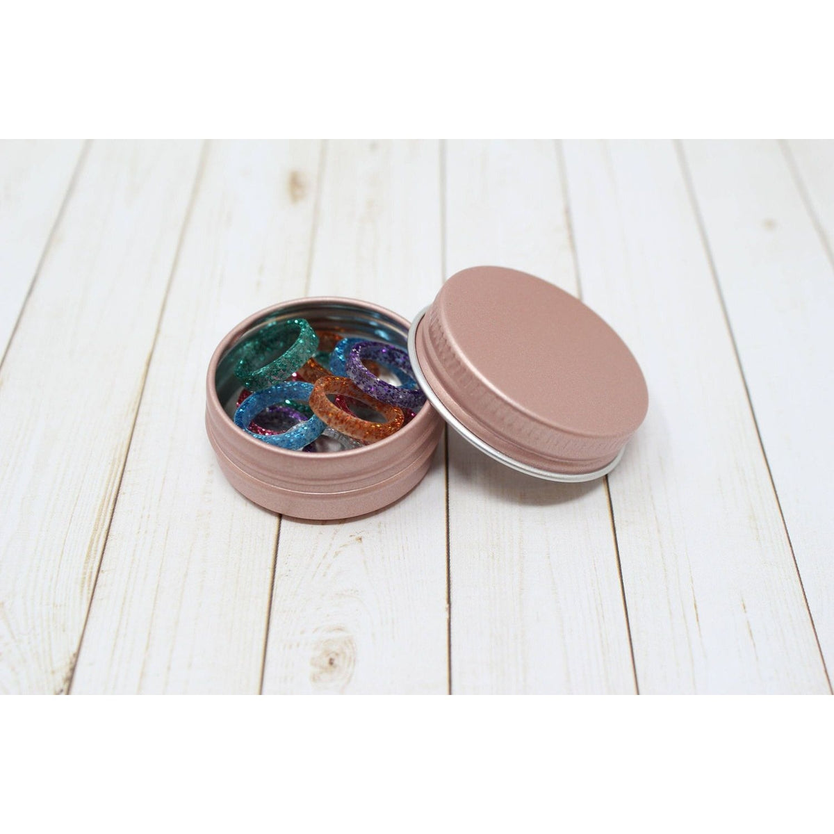 Colorful stitch markers for crocheting in a pink tin container for easy storage