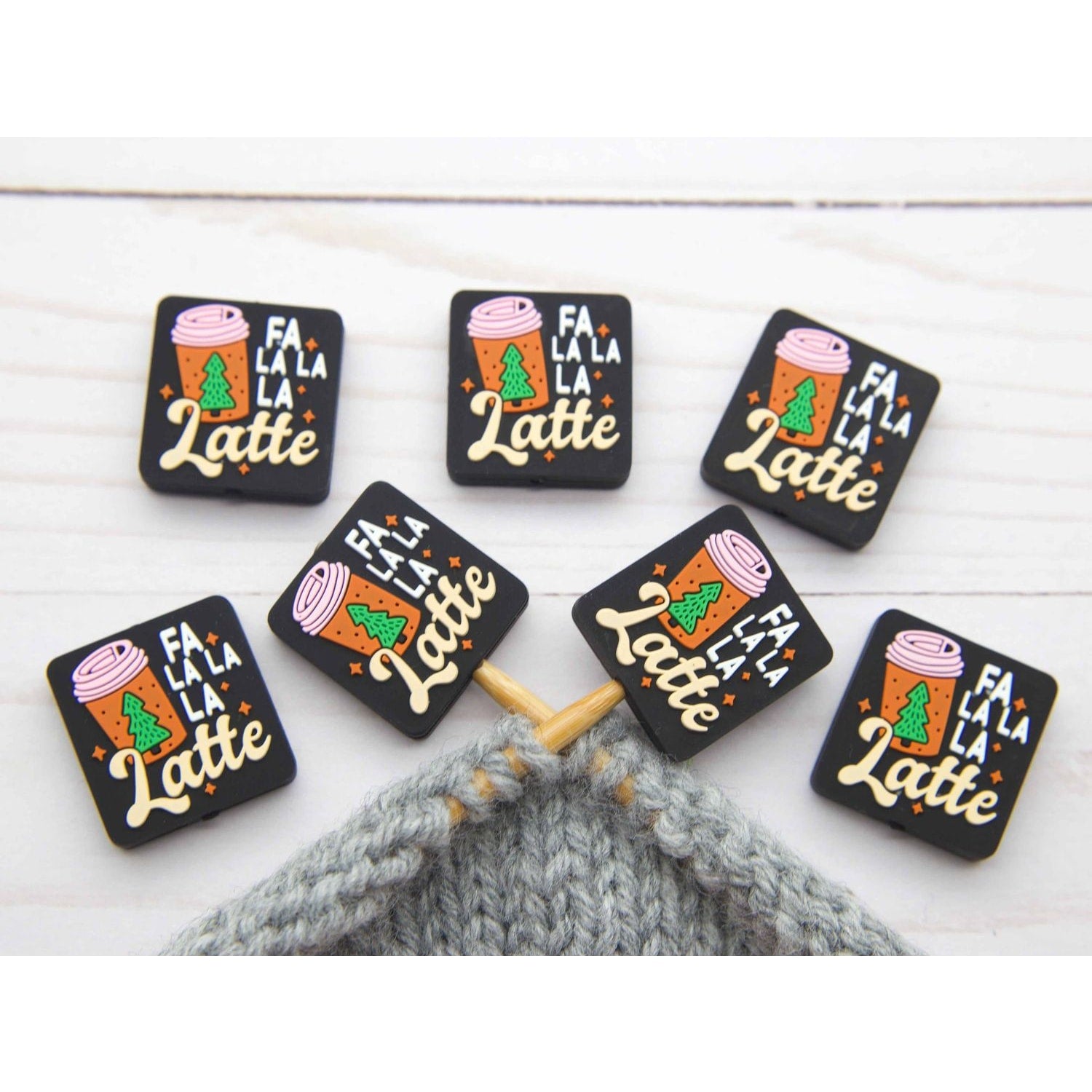 Fa La La La Latte stitch stopper set of seven black rectangular knitting stoppers with holiday latte design on gray project