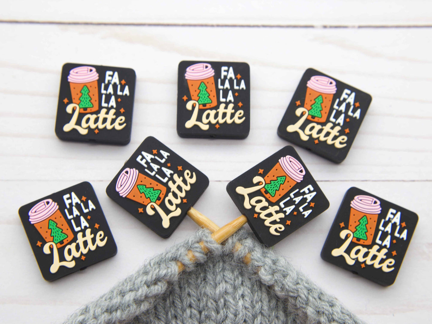 Fa La La La Latte stitch stopper set of seven black rectangular knitting stoppers with holiday latte design on gray project