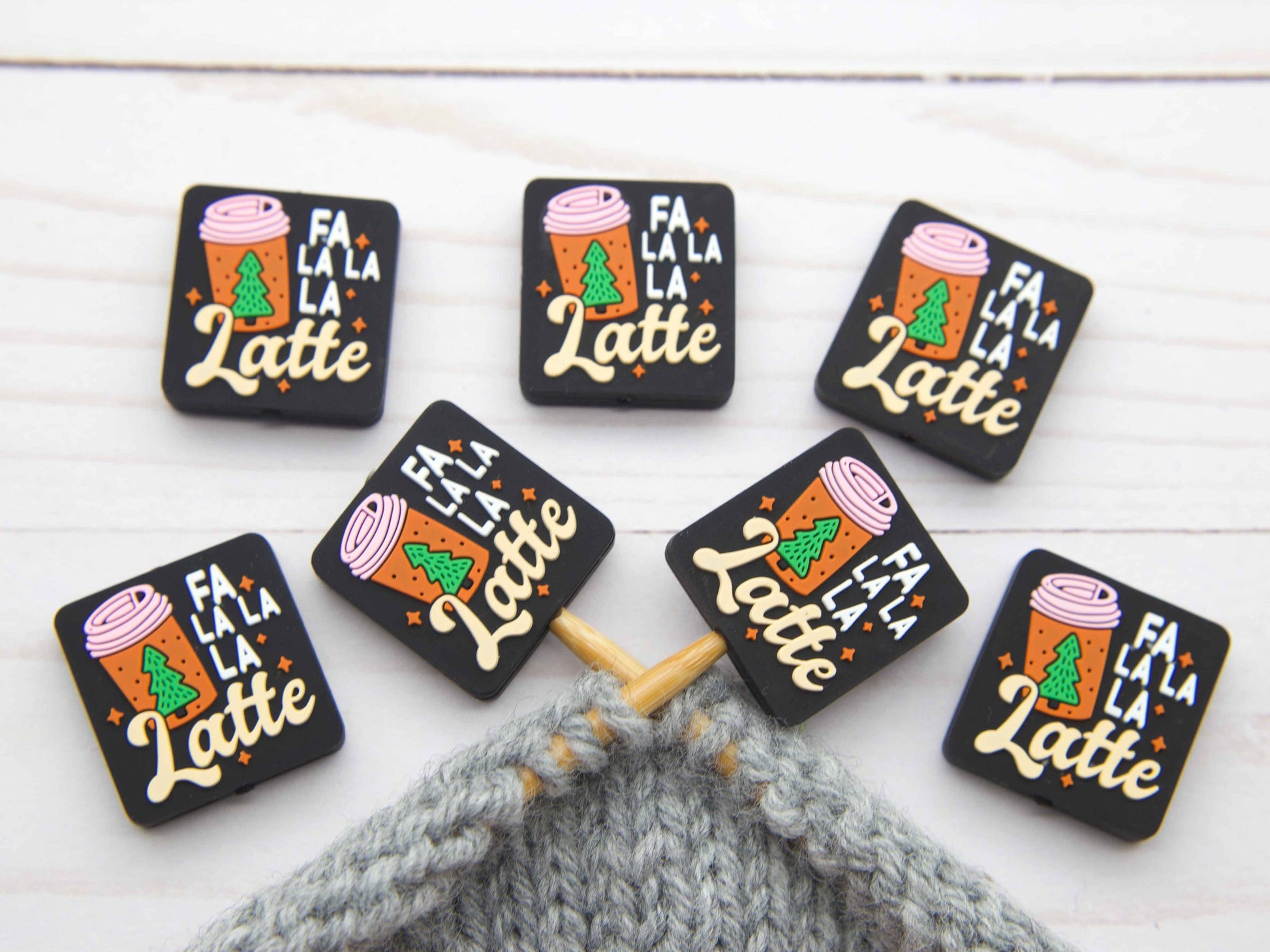 Fa La La La Latte stitch stopper set of seven black rectangular knitting stoppers with holiday latte design on gray project