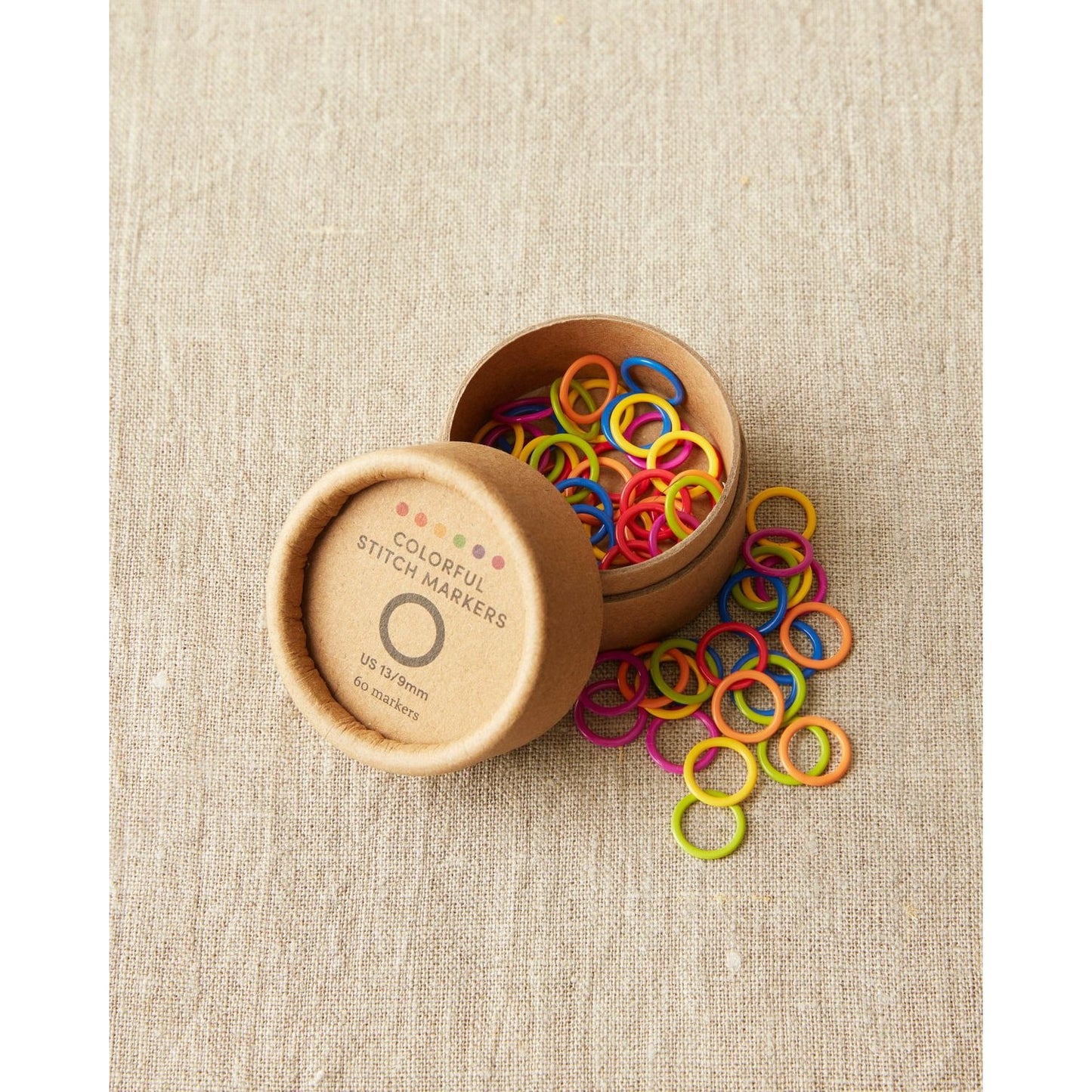 Cocoknits original stitch markers for knitting in various bright colors in a round brown container