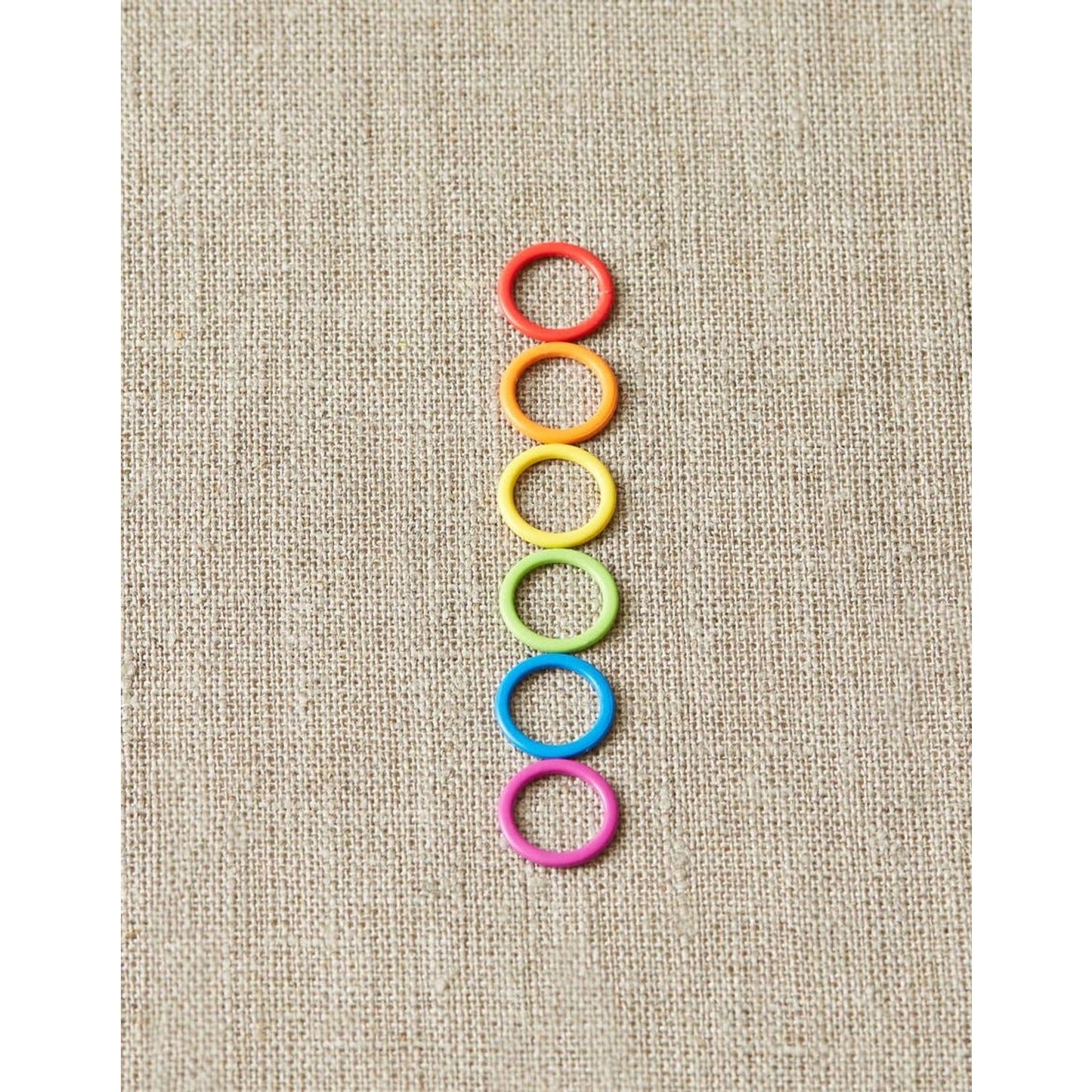 Cocoknits original stitch markers for knitting in six vibrant colors arranged vertically on fabric