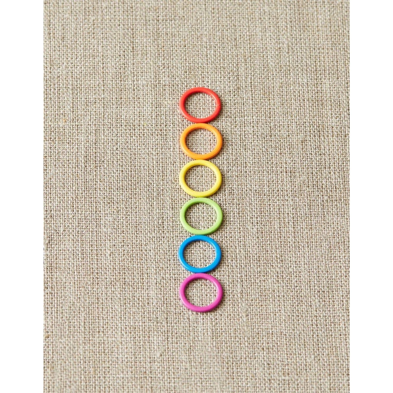 Cocoknits original stitch markers for knitting in six vibrant colors arranged vertically on fabric