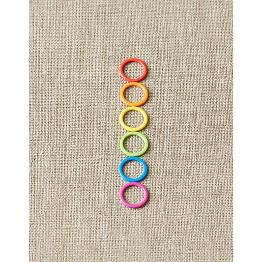 Cocoknits original stitch markers for knitting in six vibrant colors arranged vertically on fabric
