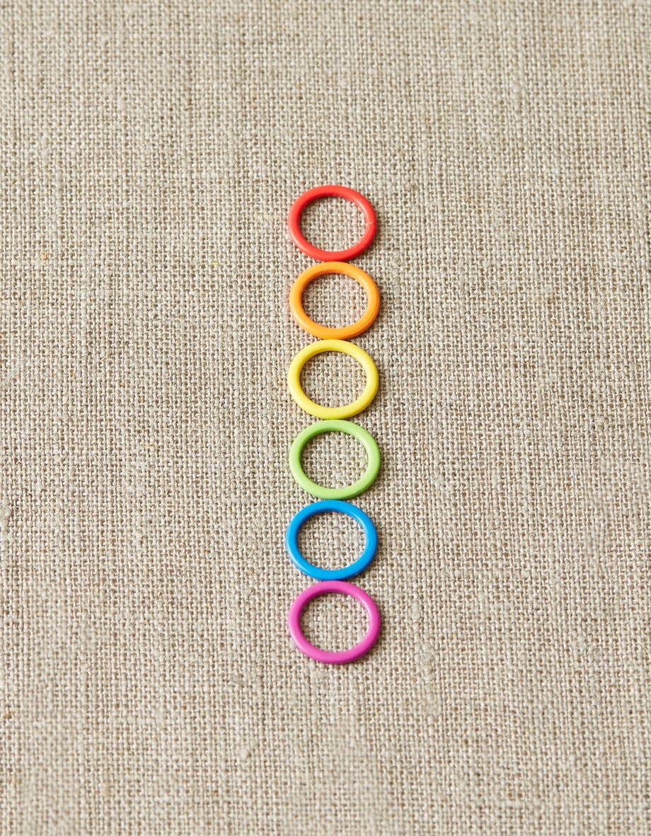 Cocoknits original stitch markers for knitting in six vibrant colors arranged vertically on fabric