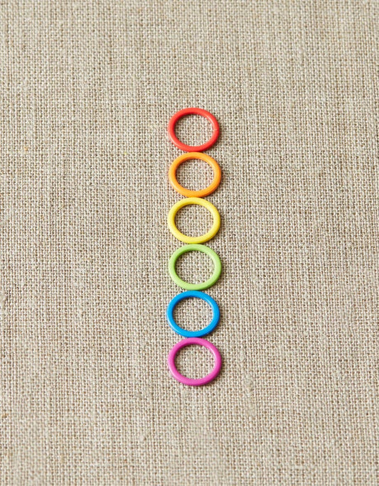Cocoknits original stitch markers for knitting in six vibrant colors arranged vertically on fabric