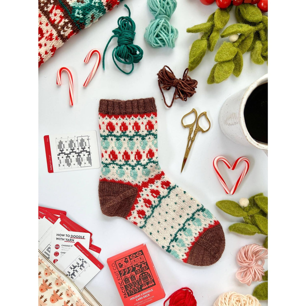Cozy handmade Christmas holiday cards displayed alongside festive crafting supplies and a knitted sock
