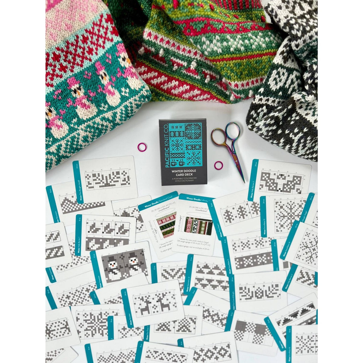 Twice Sheared Sheep deck of card surrounded by colorful knitting patterns and tools for creative projects