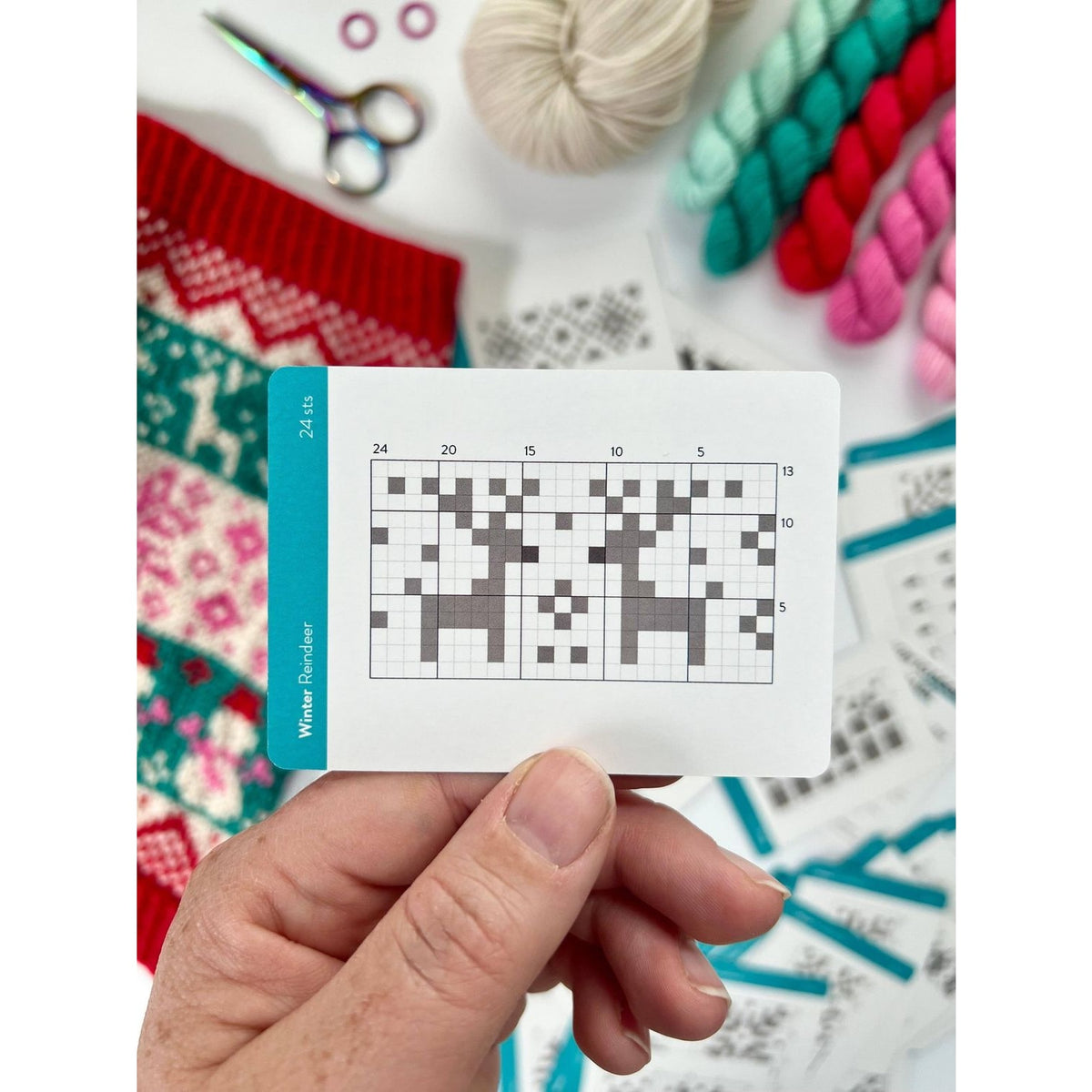 Knitting pattern chart on a card from Twice Sheared Sheep deck of card surrounded by colorful yarn and tools