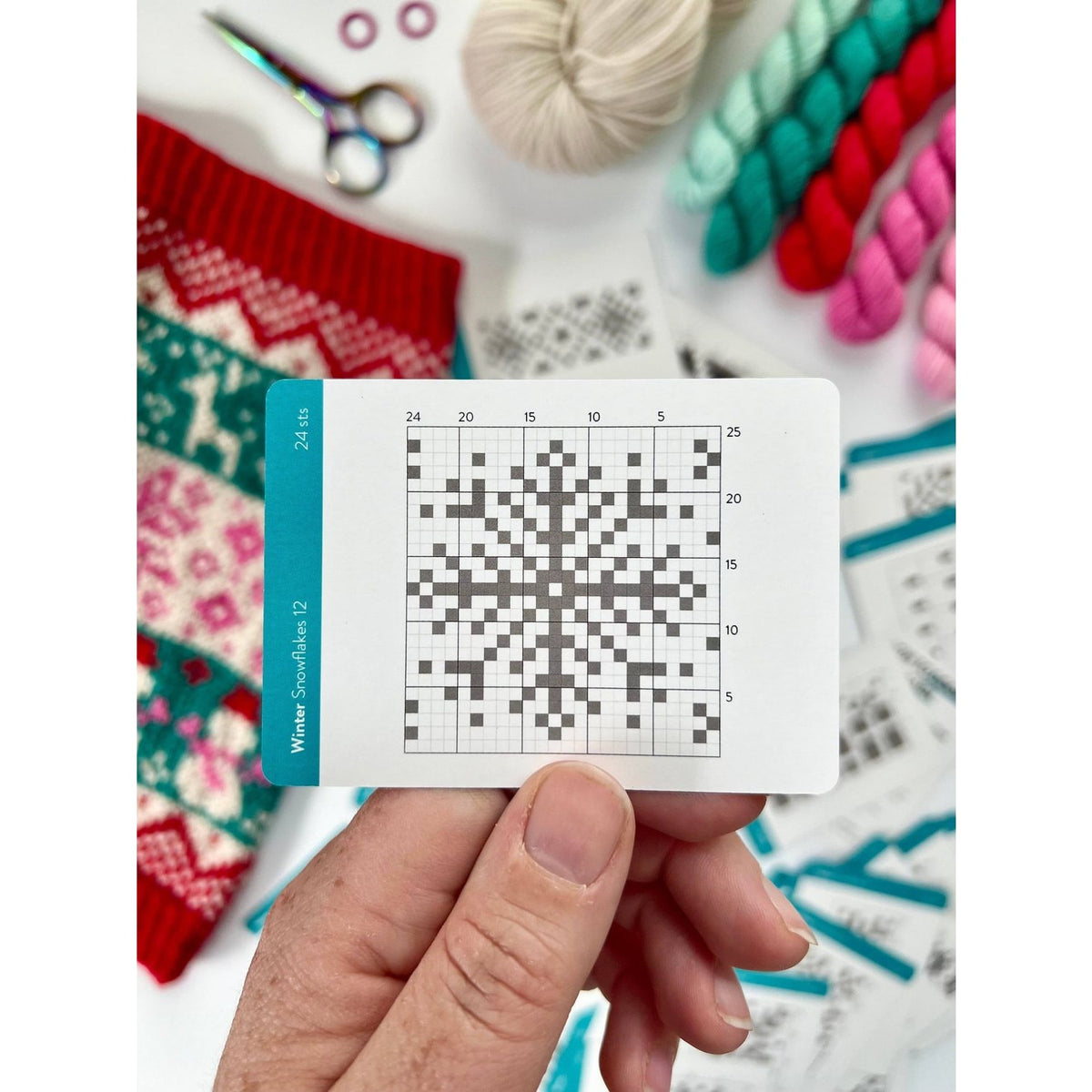 Colorful knitting patterns with a deck of card showcasing a snowflake design in grid format