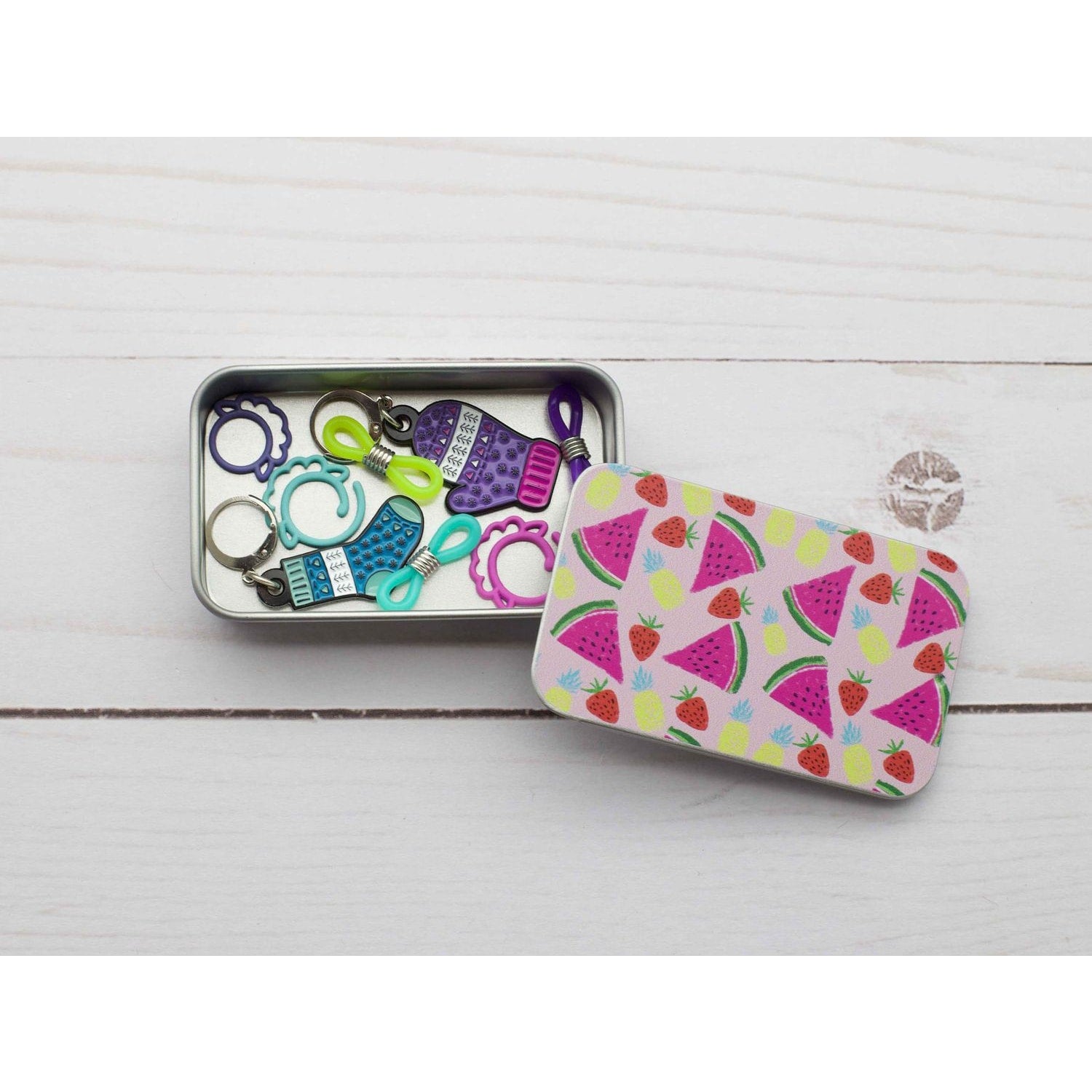 Colorful print slide top storage tins filled with sewing notions and charm accessories