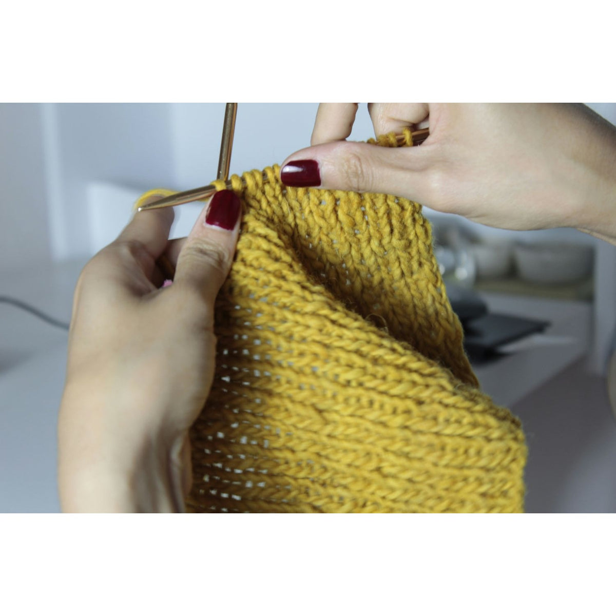 Hands holding a knitting project in yellow yarn during a private knitting lesson