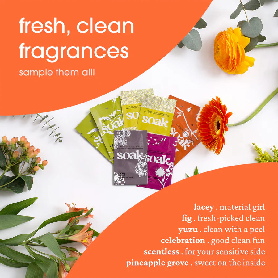 Sample pack of Soak Wholesale soap fragrances with colorful packets and fresh flowers on a table. iPad mini what size.