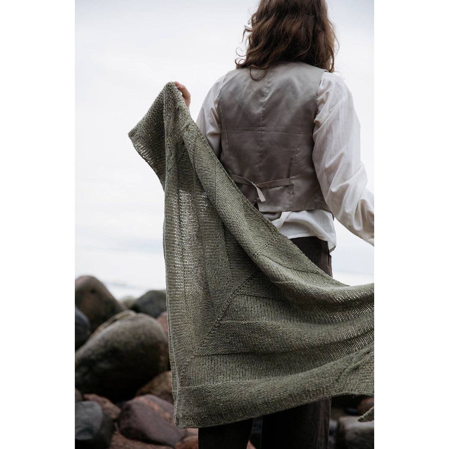 Person holding a knitted shawl outdoors, inspired by the Soothing Stitches knitting book.