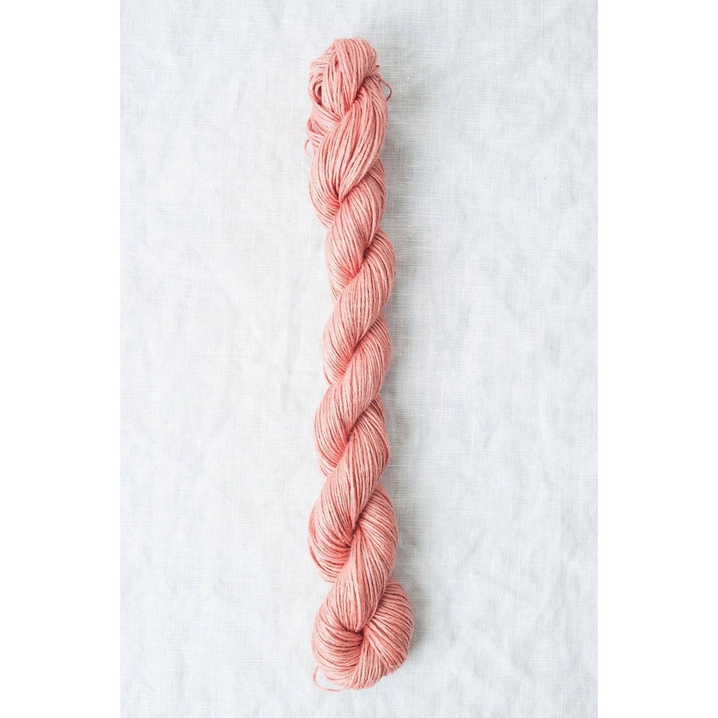 Skein of Sparrow organic linen yarn in soft pink, perfect for knitting and crocheting projects