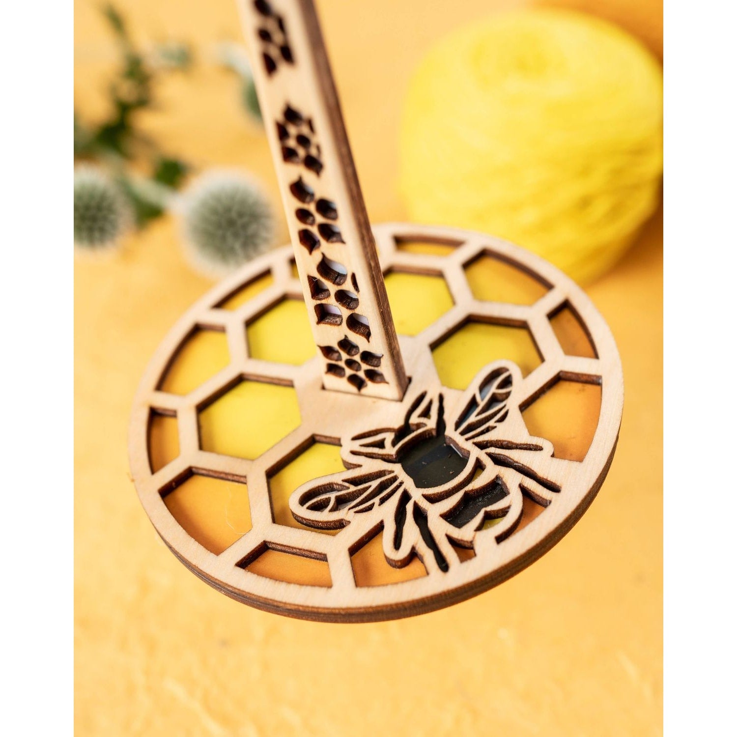 Lemonwood wooden bee knitting accessory with honeycomb cutouts and yellow yarn ball