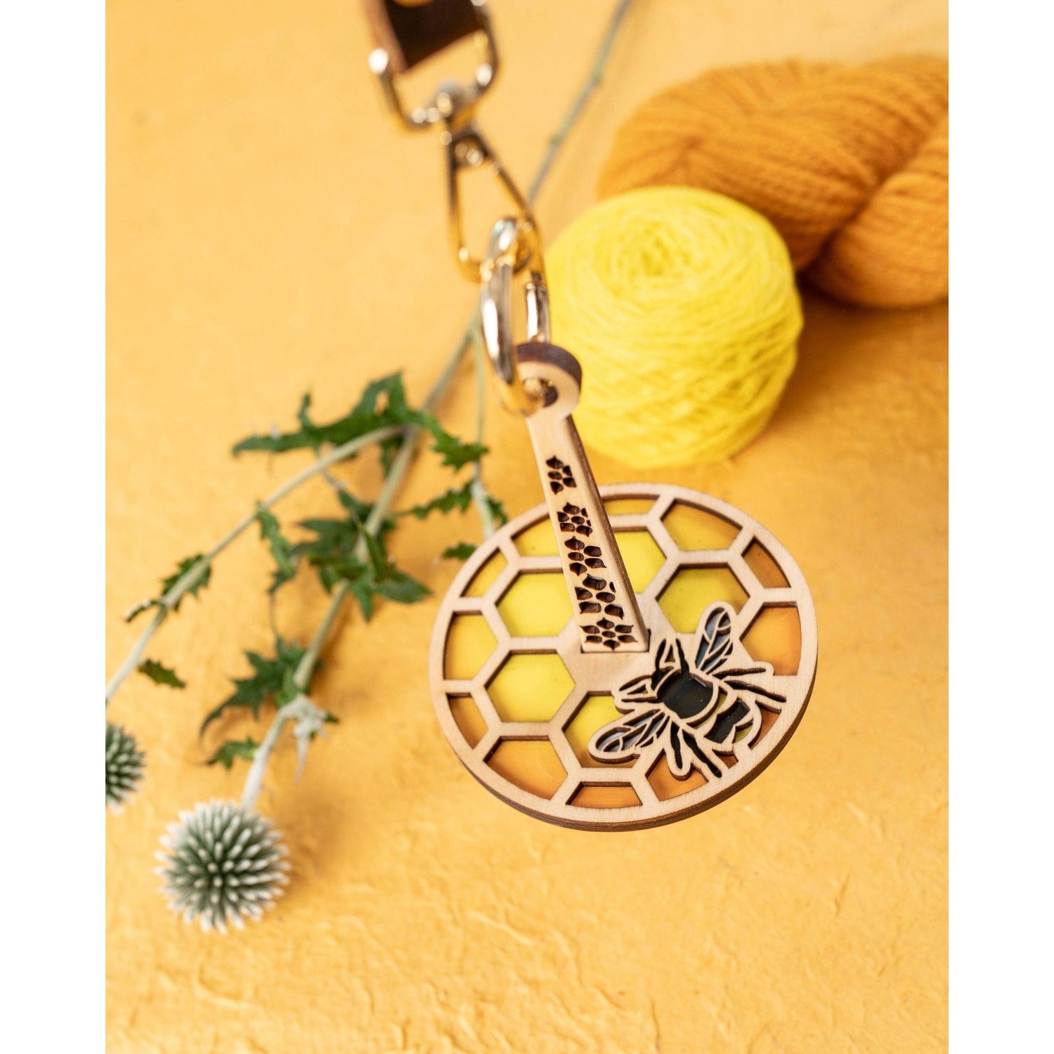 Lemonwood wooden bee knitting accessory keychain with honeycomb pattern and yellow yarn background