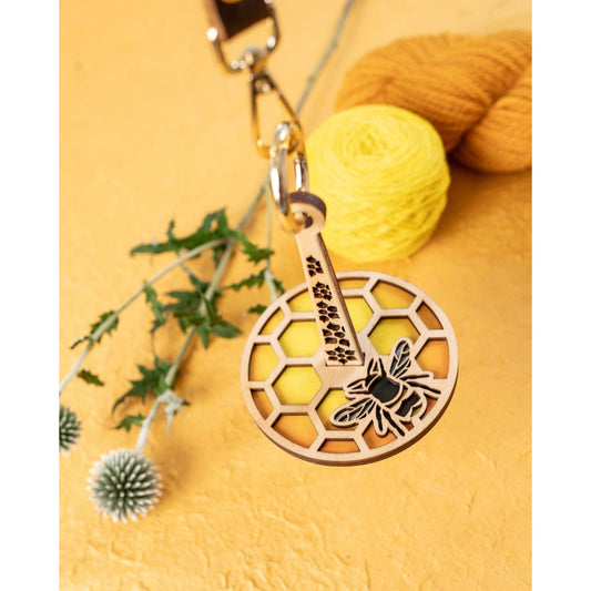 Lemonwood wooden bee knitting accessory keychain with honeycomb pattern and yellow yarn background