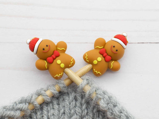 Pair of Fox and Pine Stitches gingerbread stitch stoppers on wooden needles with gray knitted fabric