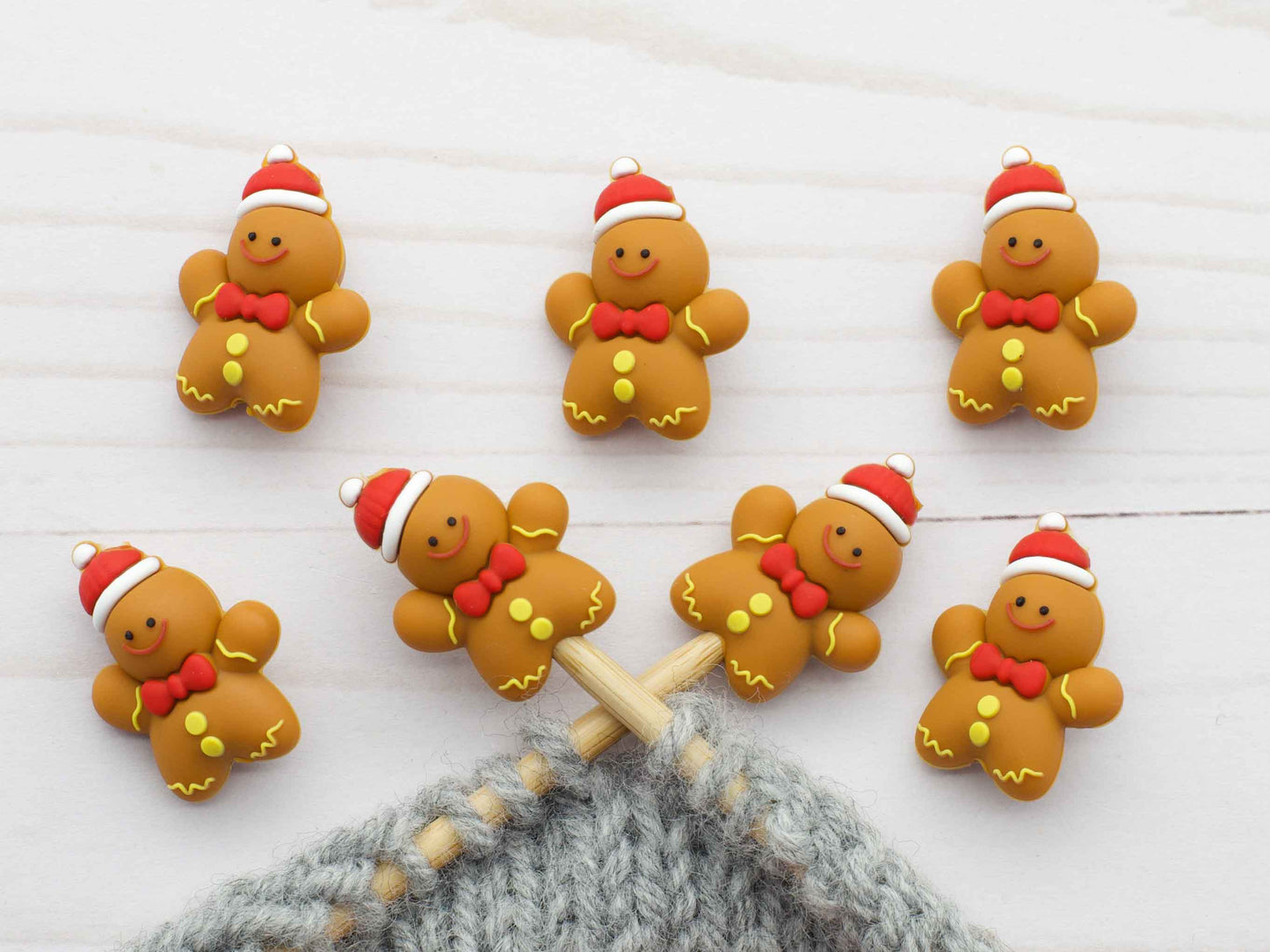 Set of six gingerbread stitch stoppers on wooden needles with grey knitting by Fox and Pine Stitches