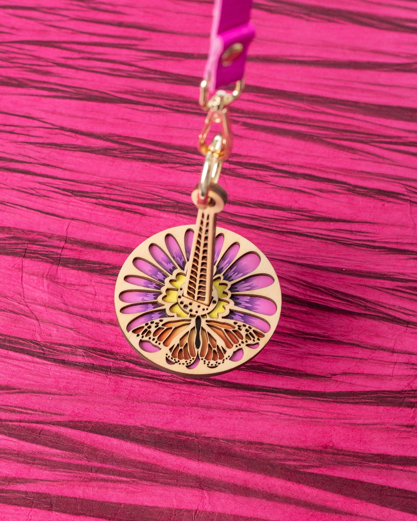 Round wooden yarn minder pendant with floral butterfly laser cut design on pink strap lemonwood monarchana yarn accessory