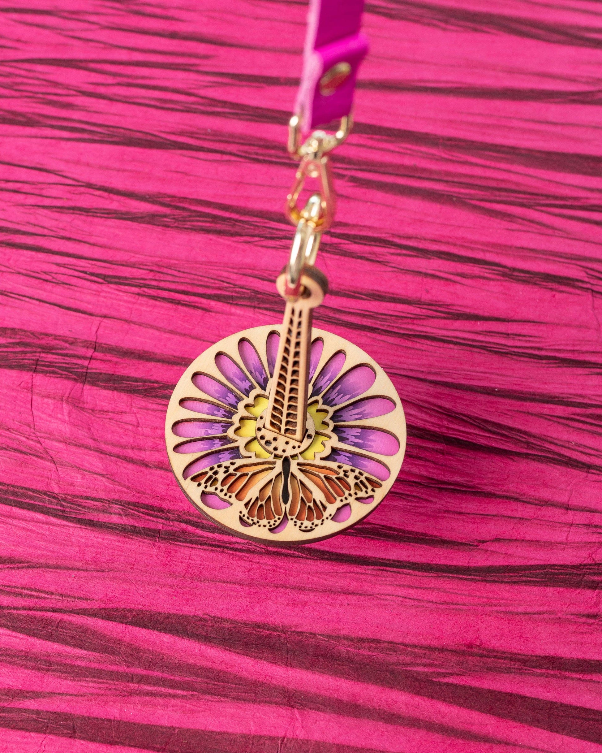 Round wooden yarn minder pendant with floral butterfly laser cut design on pink strap lemonwood monarchana yarn accessory