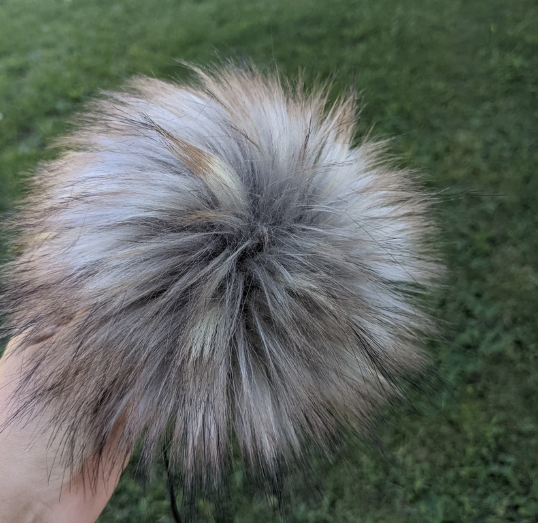 Fluffy stormy grey pom pom for crochet hats in a natural outdoor setting