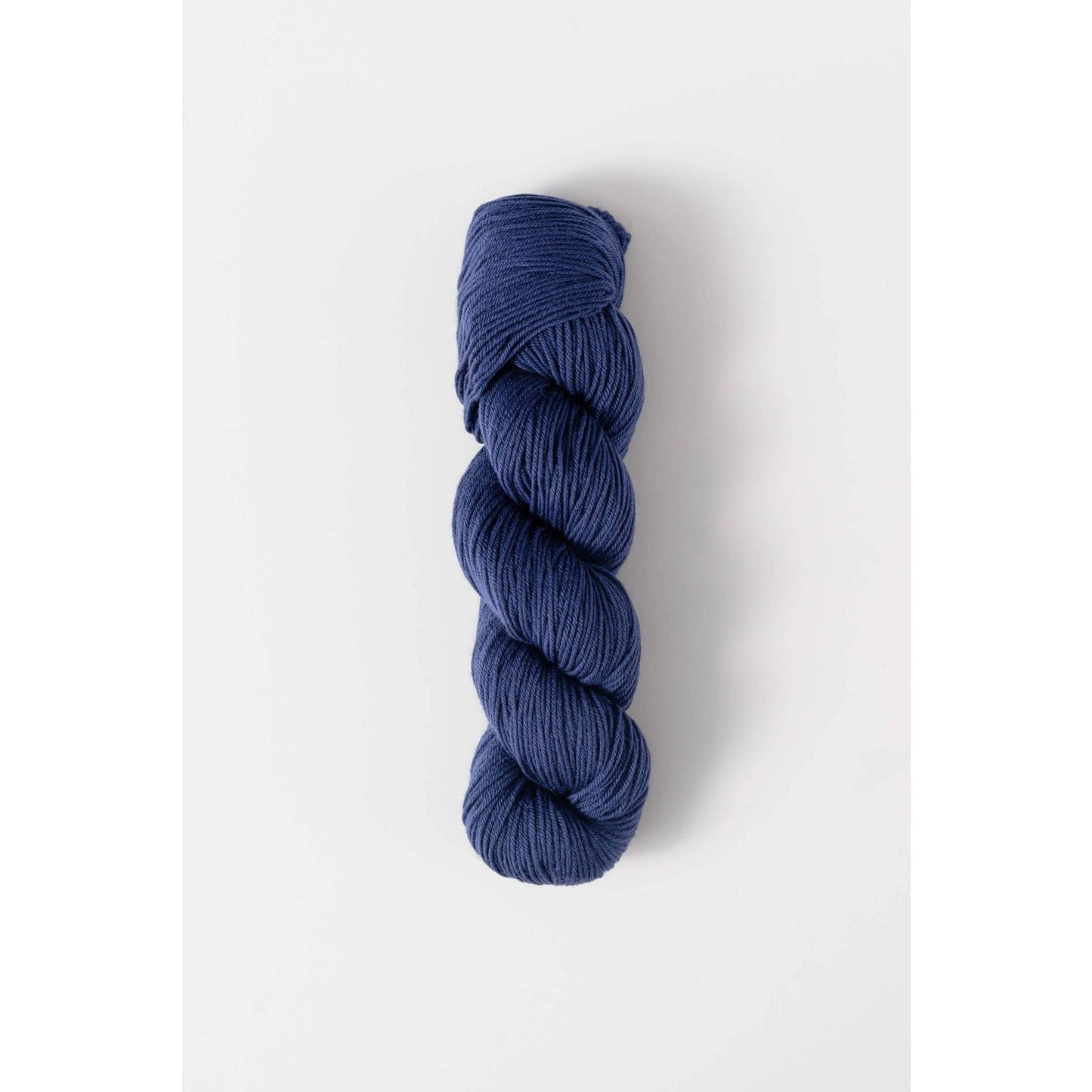 Quince and Co superwash merino fingering yarn in rich navy blue twisted skein