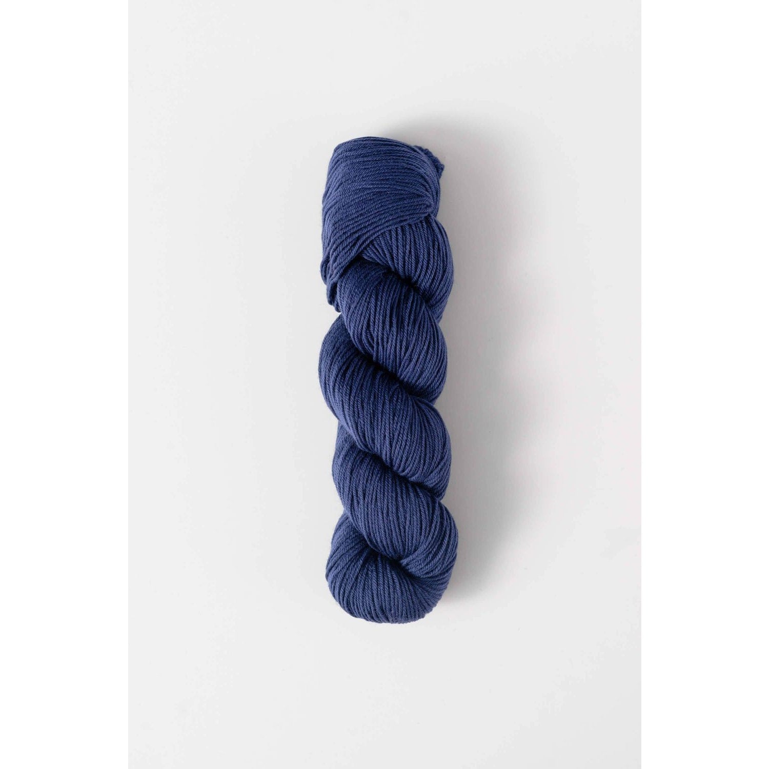 Quince and Co superwash merino fingering yarn in rich navy blue twisted skein