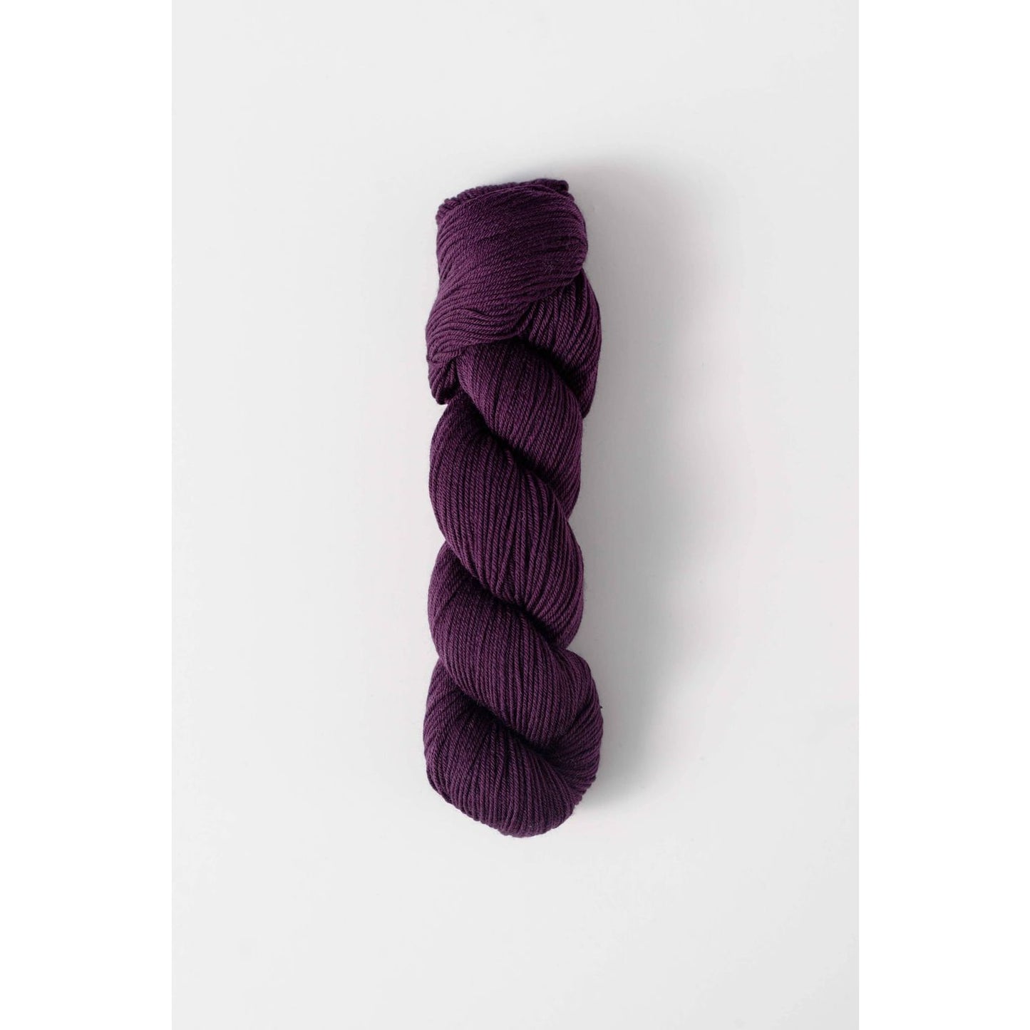 Quince and Co superwash merino fingering yarn in deep purple color skein on white background