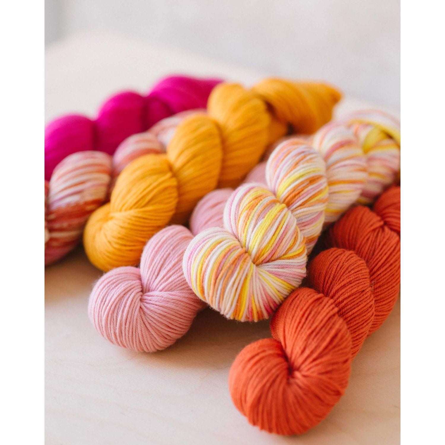 Quince & Co. superwash merino fingering yarn in vibrant colors including pink, orange, yellow, and multicolor skeins