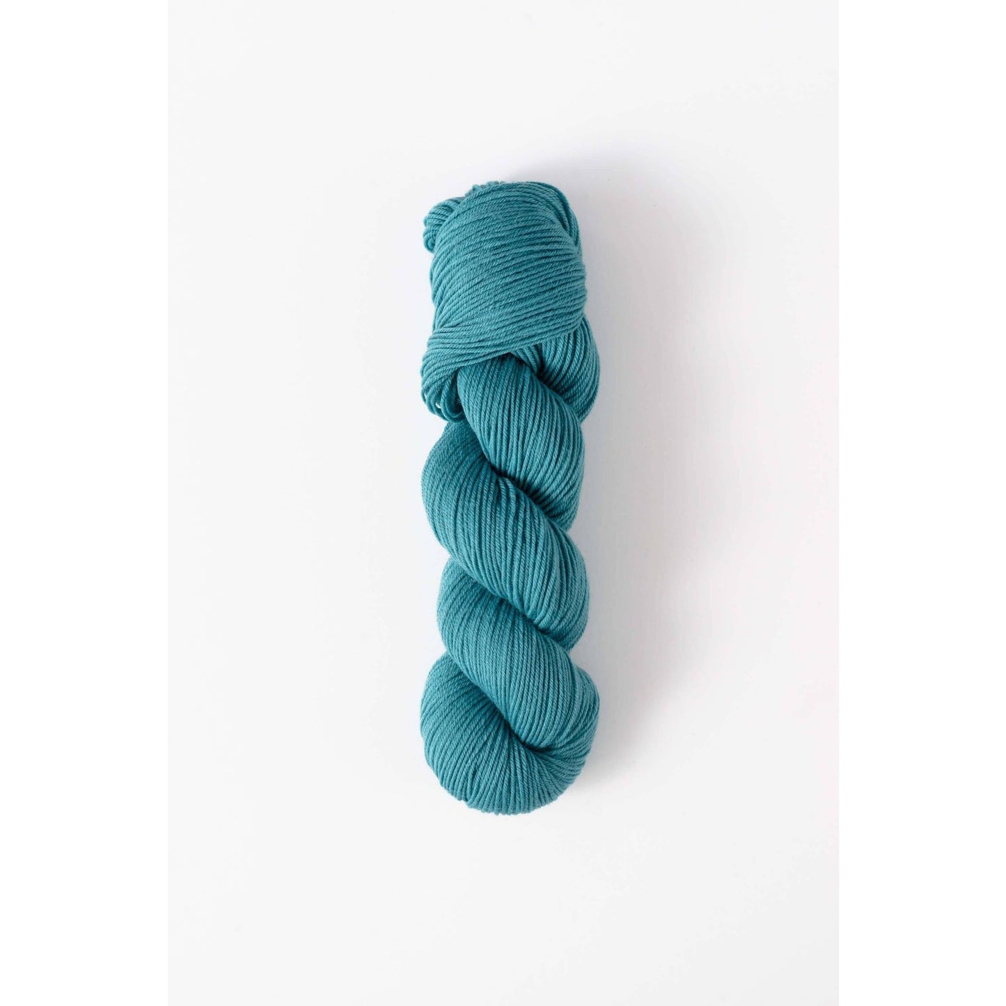 Quince & Co. superwash merino fingering yarn in teal blue skein on white background