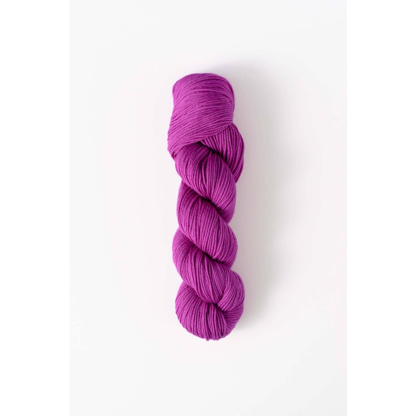 Quince and Co superwash merino fingering yarn in vibrant purple skein on white background