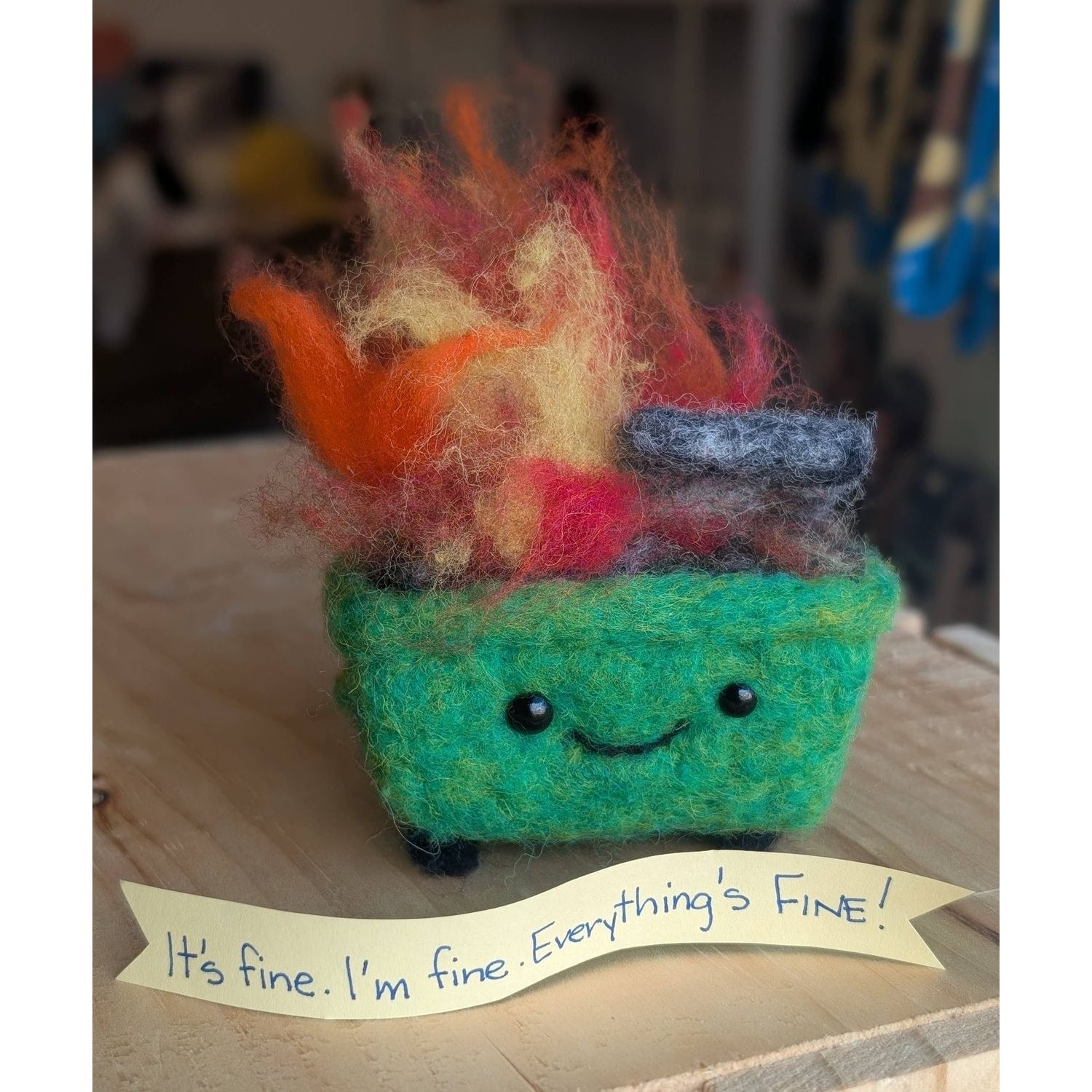 Needle felting needles with a whimsical felted dumpster fire art piece smiling cheerfully