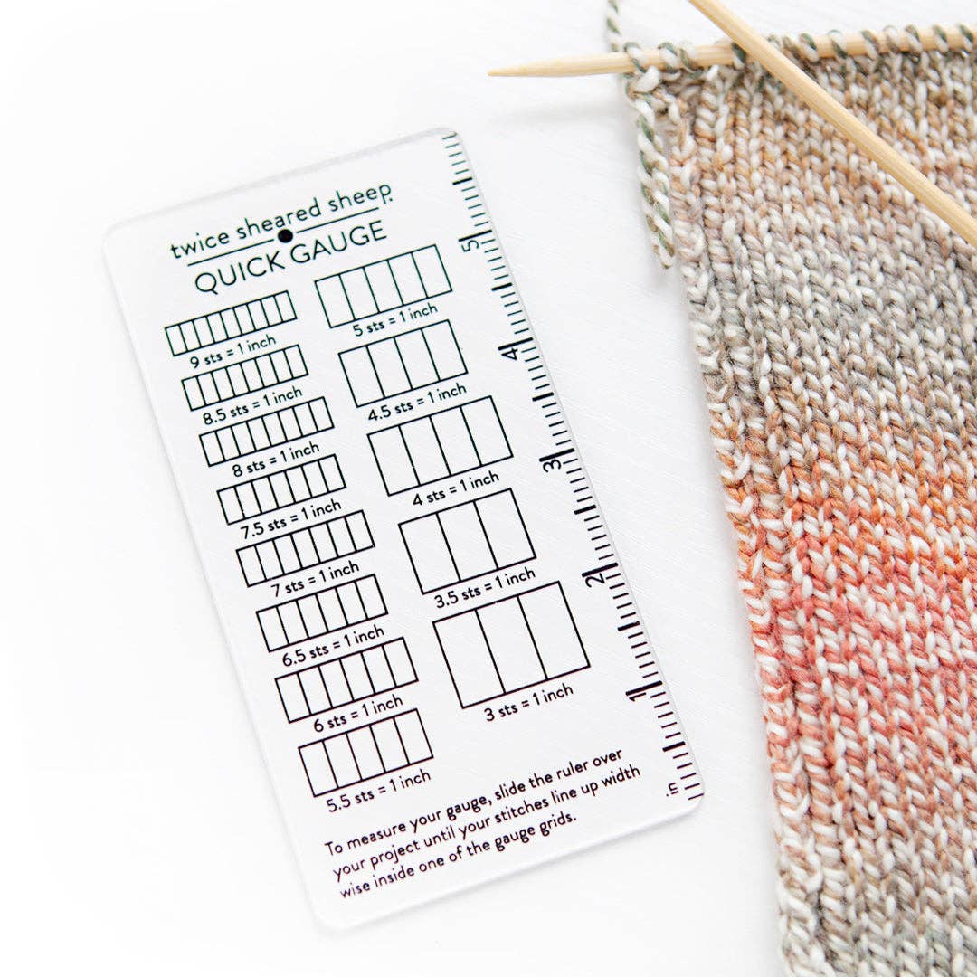 Twice Sheared Sheep Quick Gauge Tool next to a knitted fabric for knitting a gauge swatch